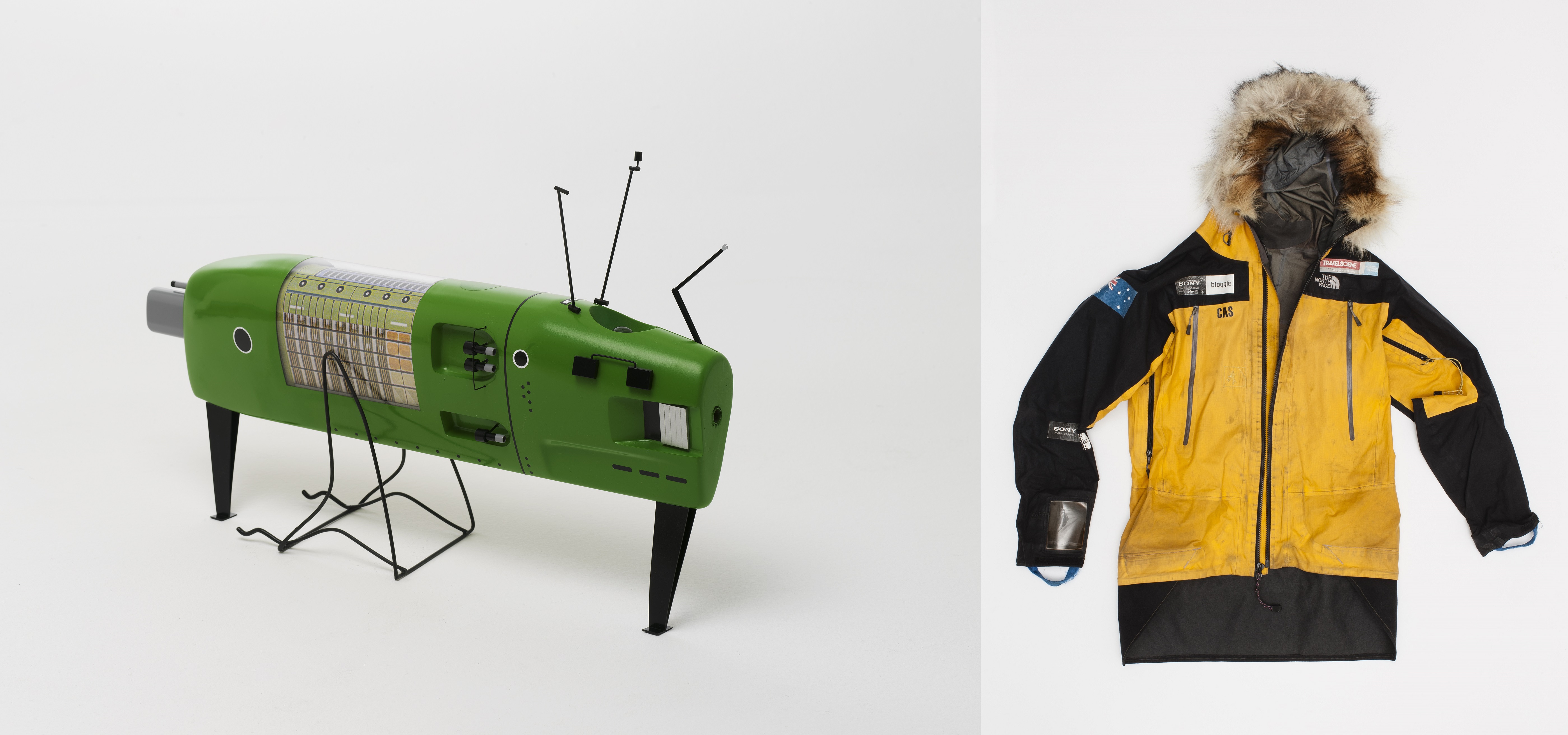 Two images side by side. Left: Model of a green submarine. There are various panels and instruments on the exterior of the vehicle. Right: Black and yellow weatherproof jacket with fur around the hood. There is an Australian flag on one sleeve and the name 'CAS' written on the chest.